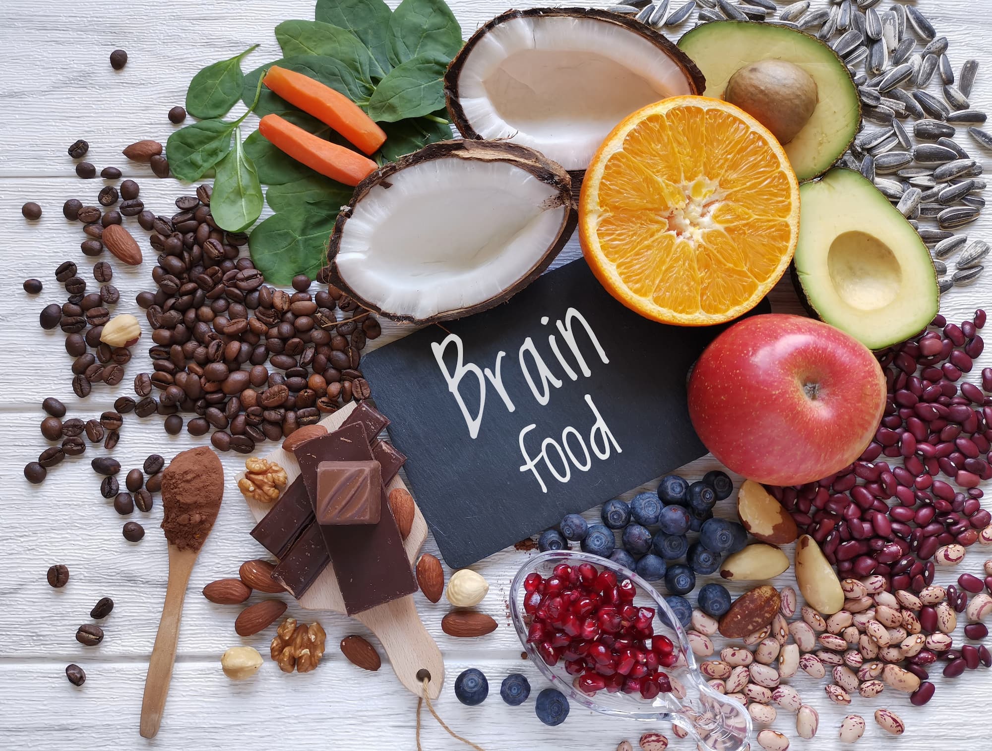 A bunch of diverse, nutritious, and healthy food for the brain on a table, surrounding a note saying "Brain Food."