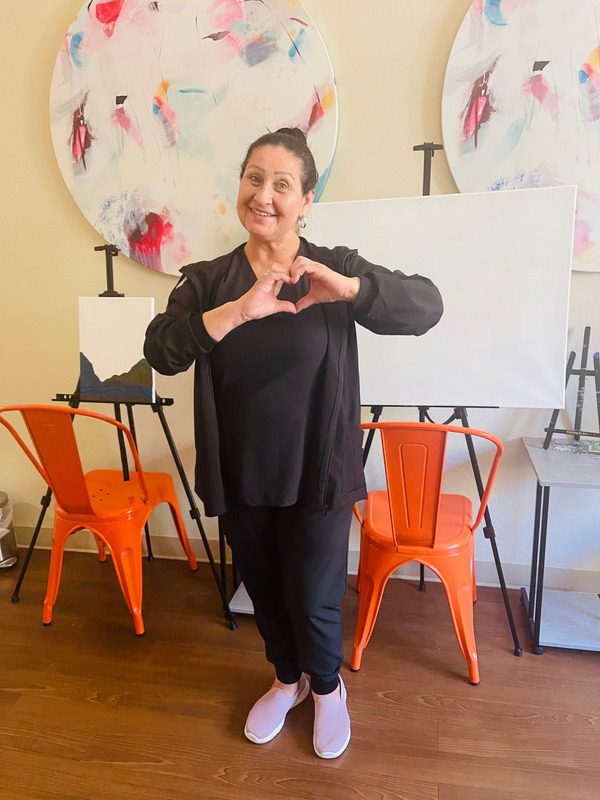 Park Senior Villas staff member with scrubs smiling while her hands make a heart