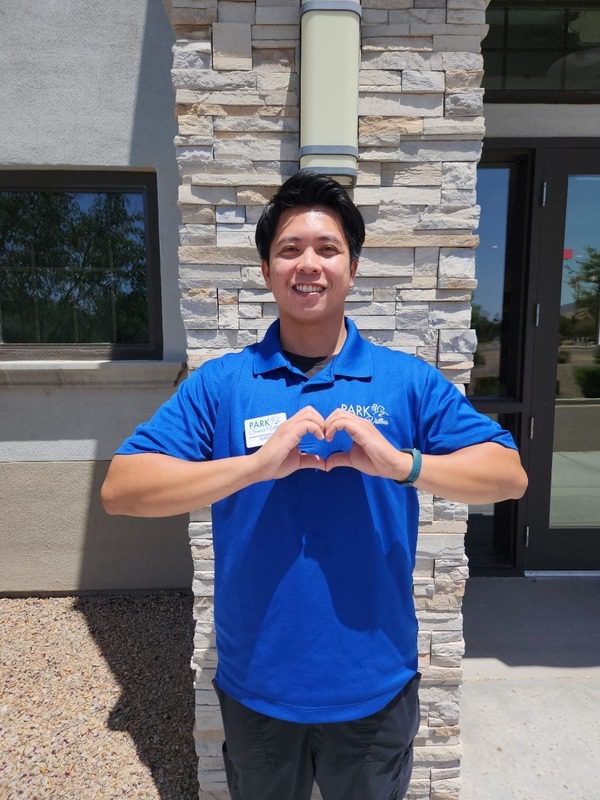 Park Senior Villas staff member outside making a heart with their hands as he smiles