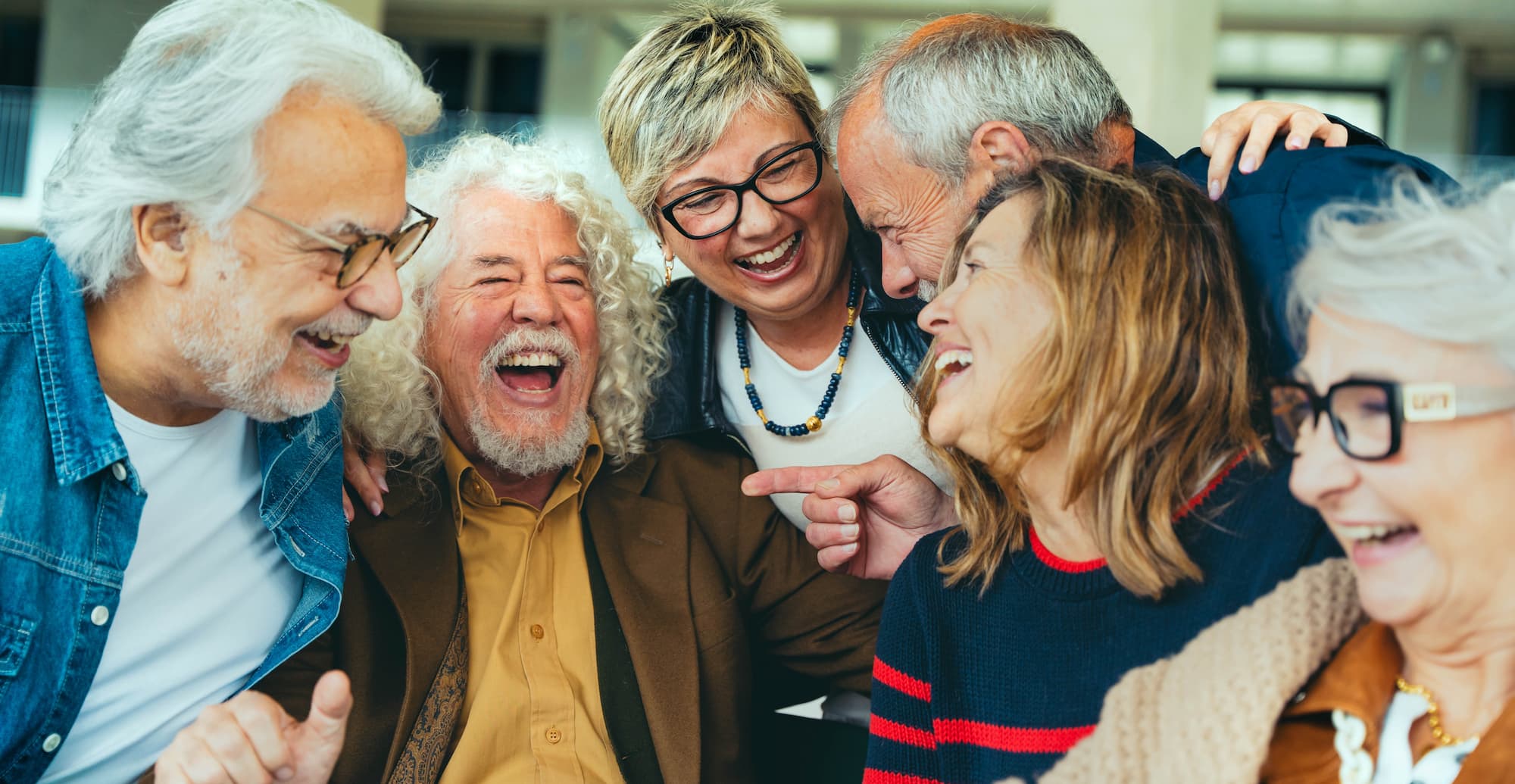 group of senior friends huddled around each other and laughing