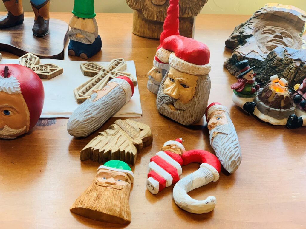 a collection of carvings from Jerry, including a cross and santa heads.
